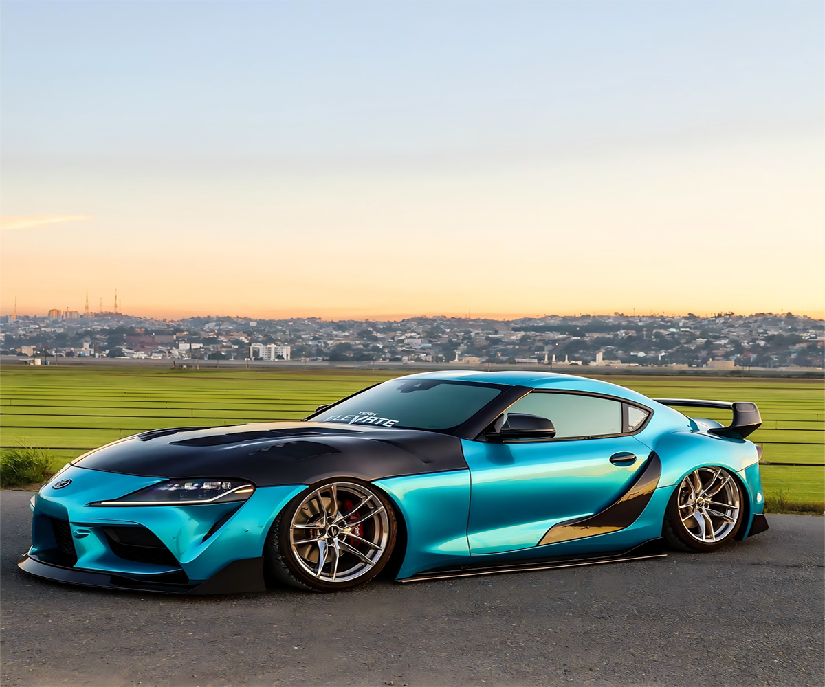 Exotic performance sports car coated in high-gloss atomic teal blue film under direct sunlight
