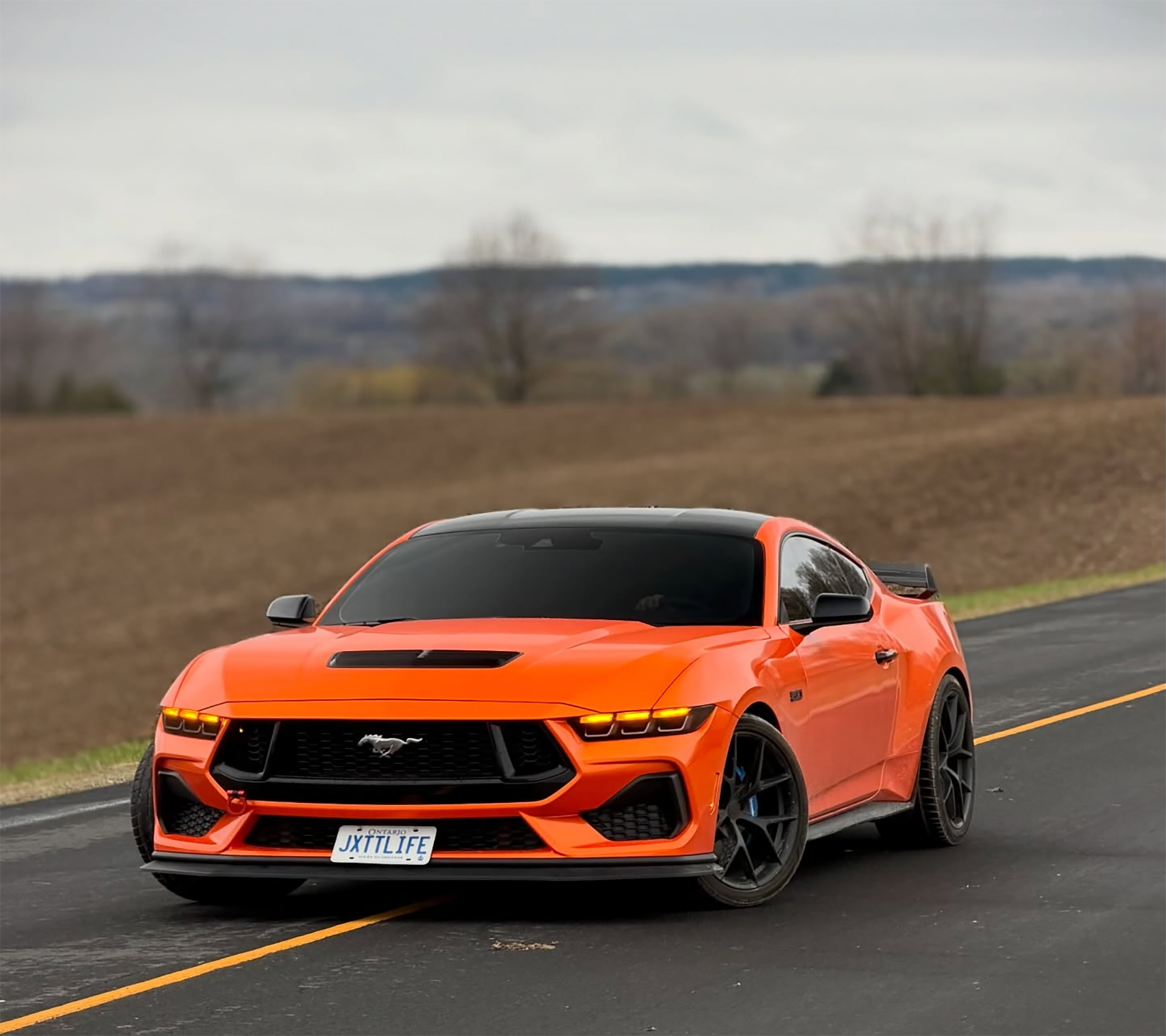 Professional installation of a high quality metallic fiery orange car wrap vinyl on a curved vehicle bumper panel