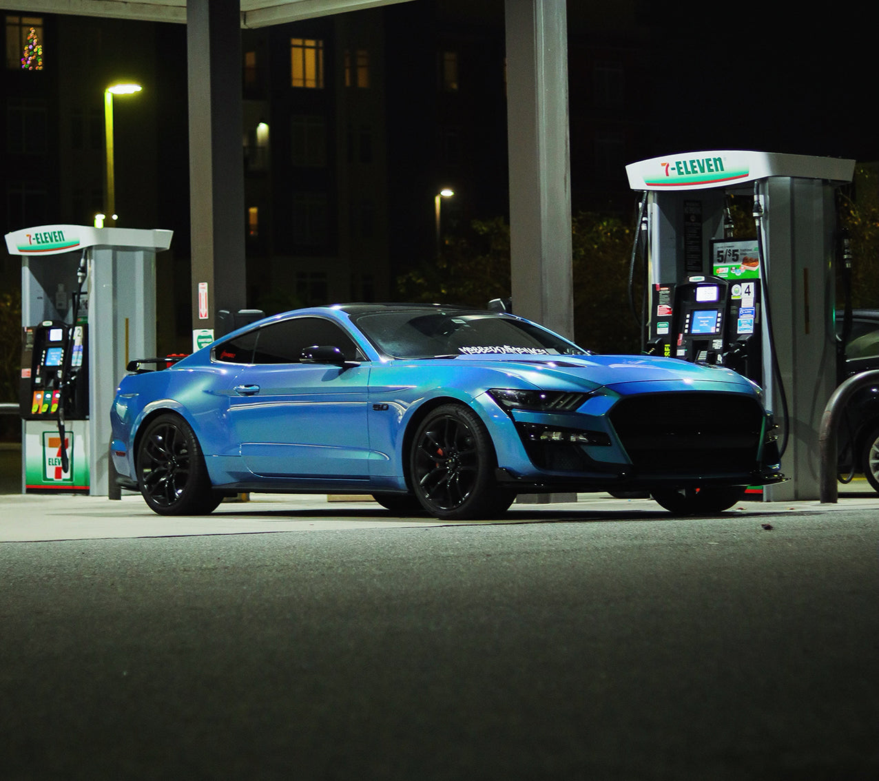 A luxury sports car showroom display showcasing a premium gloss metallic blue car wrap finish