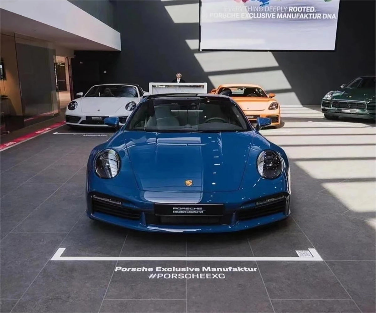 A luxury sedan expertly upgraded with a striking petrol blue vinyl wrap under bright sunlight