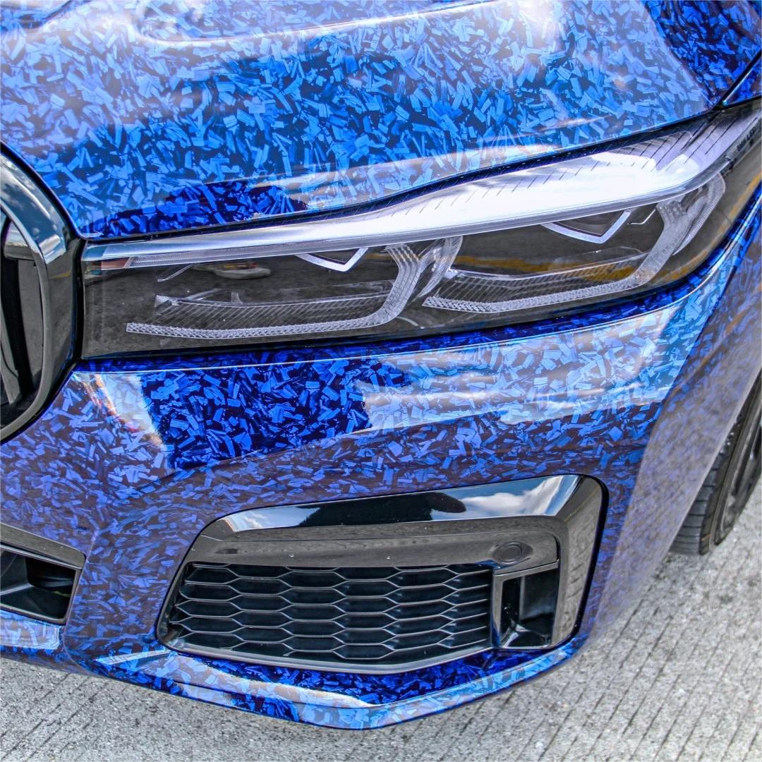 An aggressive exotic supercar completely wrapped in ALUKOCARWRAP Gloss Blue Car Wrap, showcasing a randomized blue forged carbon fiber pattern across the body.