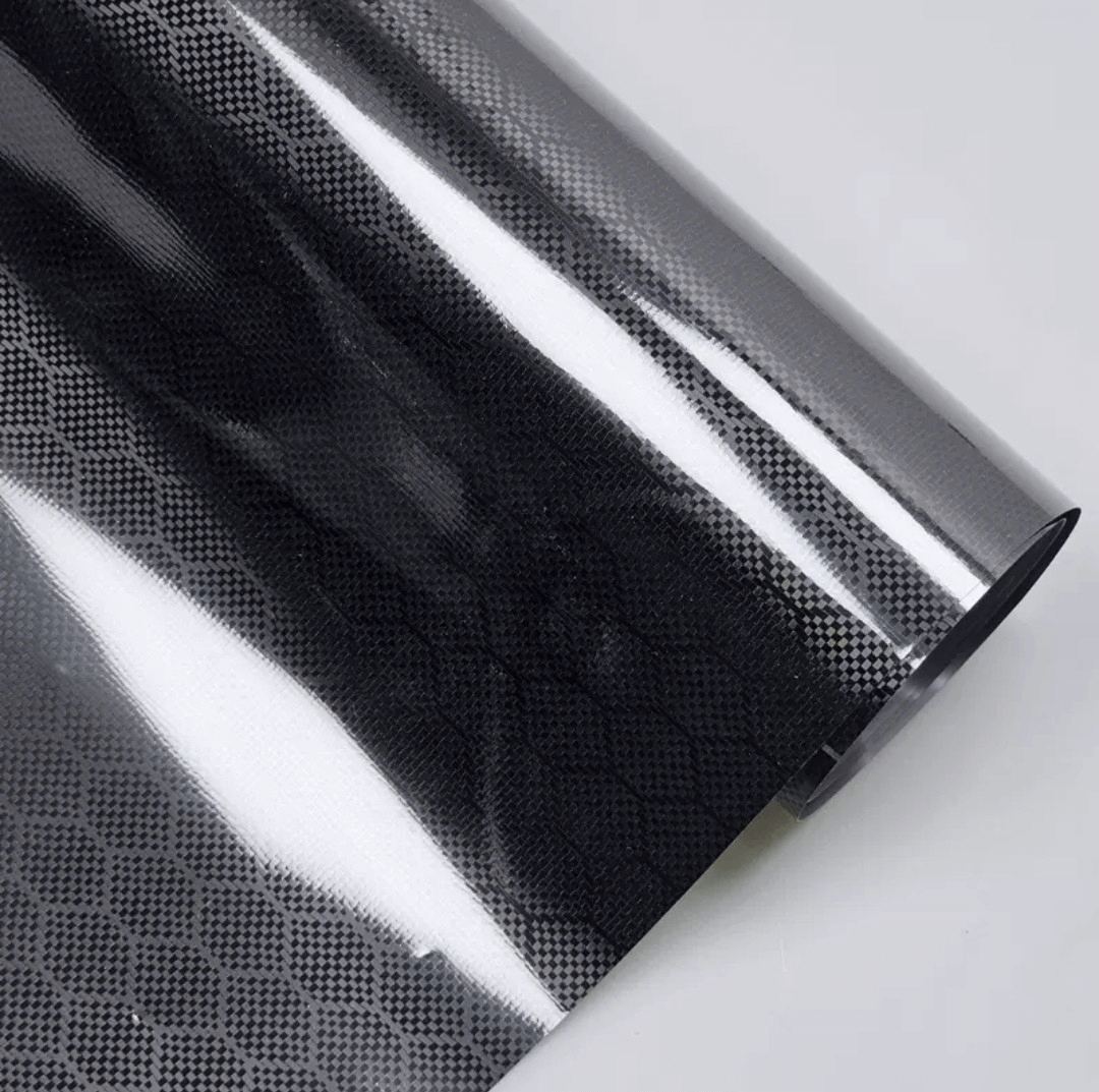 Gloss black honeycomb carbon fiber car vinyl wrap with PET liner applied on a luxury vehicle.
