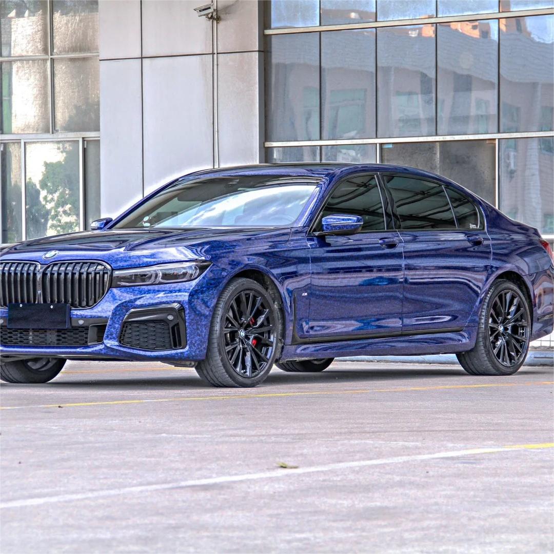 An aggressive exotic supercar completely wrapped in ALUKOCARWRAP Gloss Blue Car Wrap, showcasing a randomized blue forged carbon fiber pattern across the body.