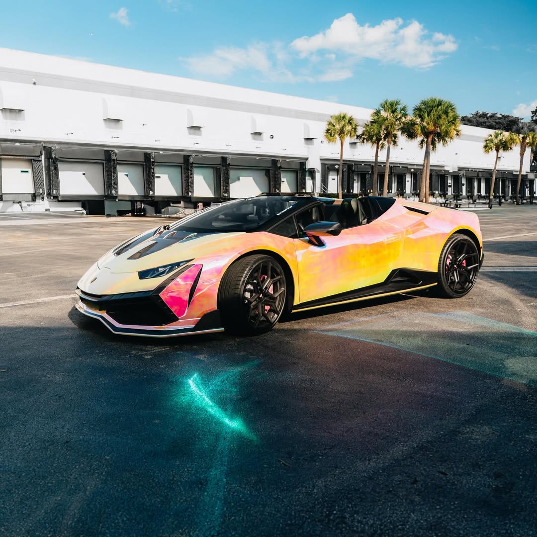 A modified hypercar wrapped in Gloss Rainbow Chrome Holographic Pink Car Vinyl Wrap, capturing intense neon laser flares.
