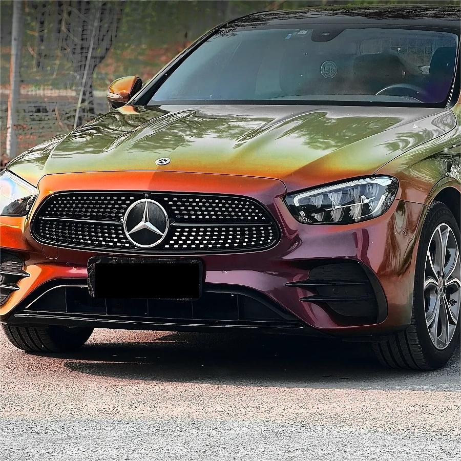 A sportscar completely covered in ALUKOCARWRAP Sunrise Morning Car Wrap, displaying a dramatic liquid gold and deep red metallic shift across the car doors and quarter panels.