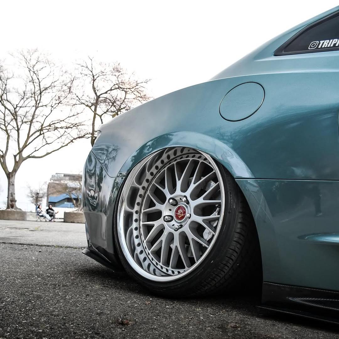 A split-angle close-up demonstrating the stark contrast of a seamless edge tucked perfectly on a hood using ALUKOCARWRAP's non-orange-peel Gloss Green Car Wrap.