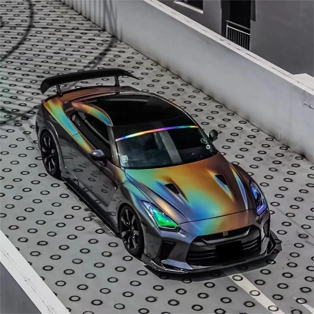 Sci-fi sports car styled with a flip psychedelic grey car wrap by ALUKOCARWRAP, displaying full-spectrum rainbow laser reflections under daylight.