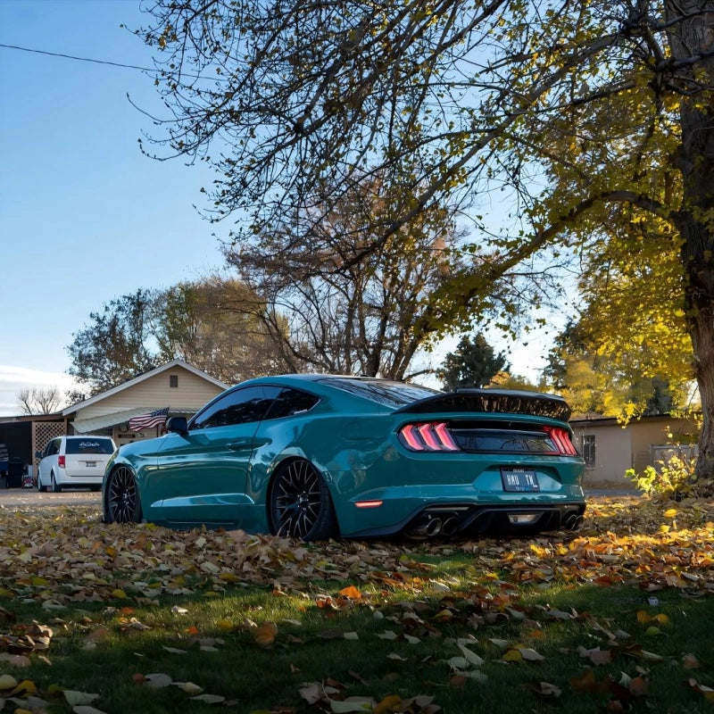 Side-angle view of gloss Storm Green car vinyl wrap PET premium film, capturing the deep liquid-metal texture under clear sunlight.
