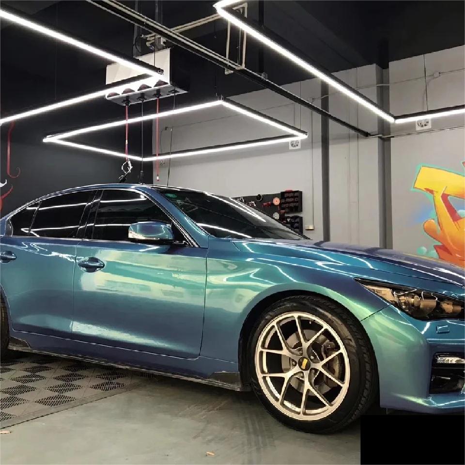 Mirror-like wet gloss reflection on a custom vehicle using premium Chameleon Green Car Wrap vinyl under clear midday sun.