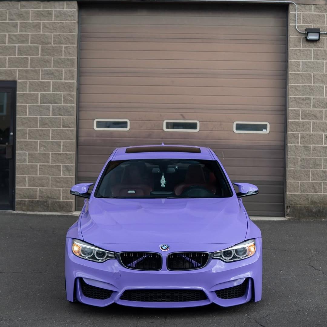 Sleek BMW sport coupe featuring a high-gloss lavender purple vinyl wrap with PET liner, highlighting the vehicle dynamic body lines and aggressive styling.