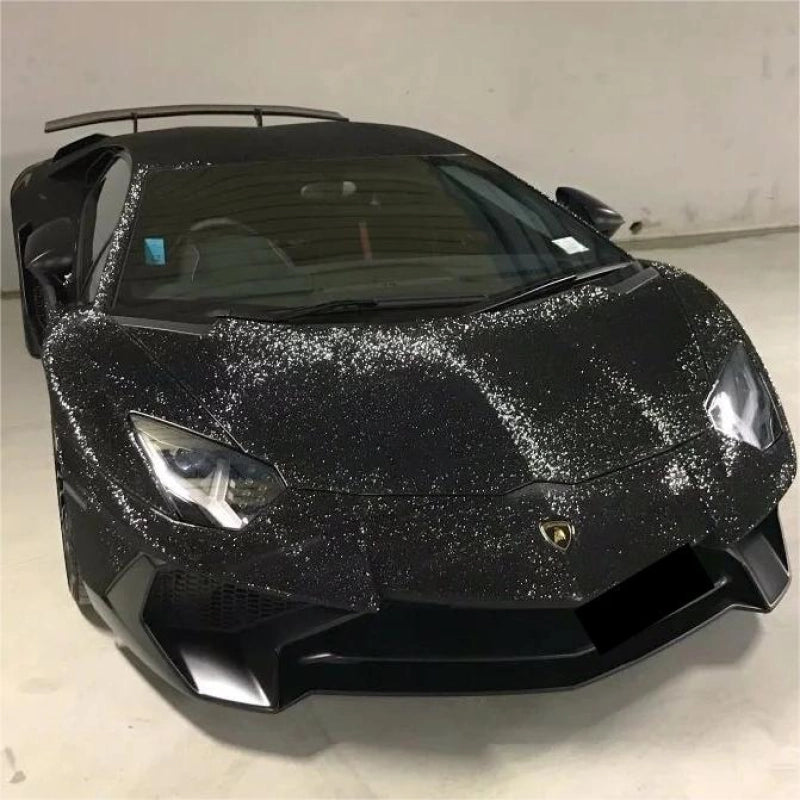Aggressive car front bumper covered in matte black vinyl wrap with diamond glitter, sparkling dark automotive styling.