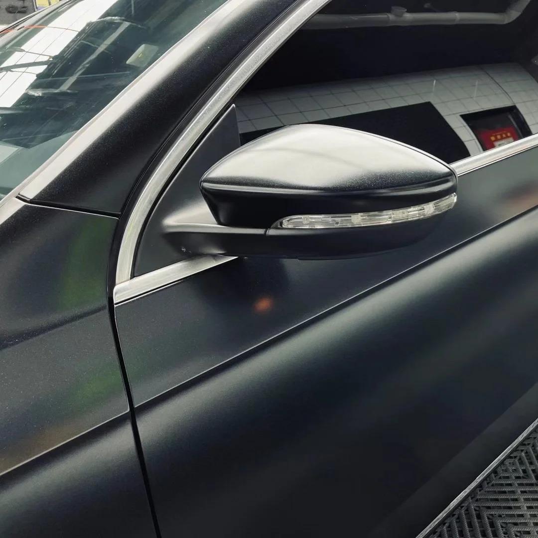 Dramatic body lines defined by an ALUKOCARWRAP matte metallic black wrap layer, displaying a subtle subterranean metallic black sheen under direct sunlight.