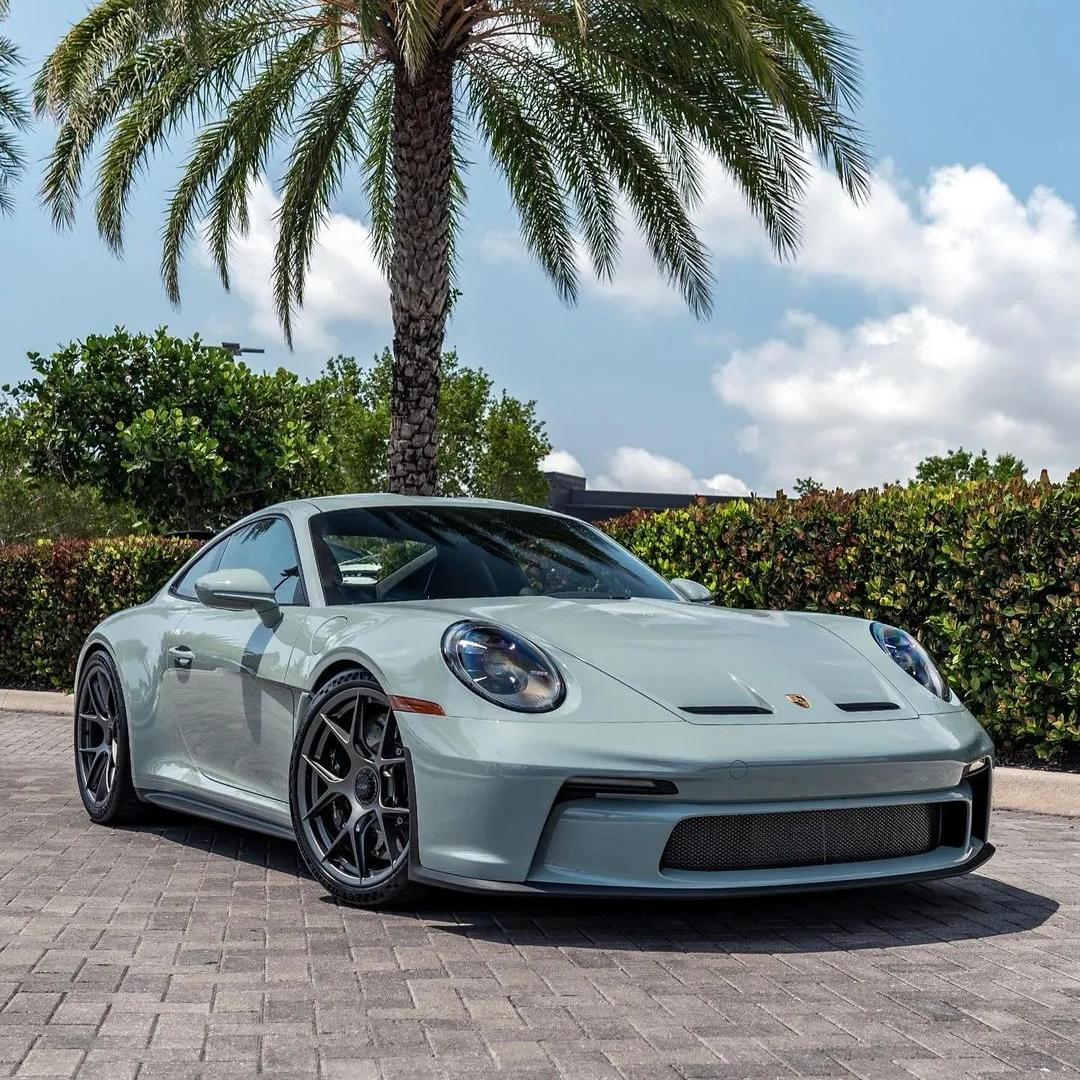 Close-up profile of a modern sports car enveloped in gloss metallic shade green vinyl wrap, exhibiting unique color-shifting undertones under outdoor sunlight.