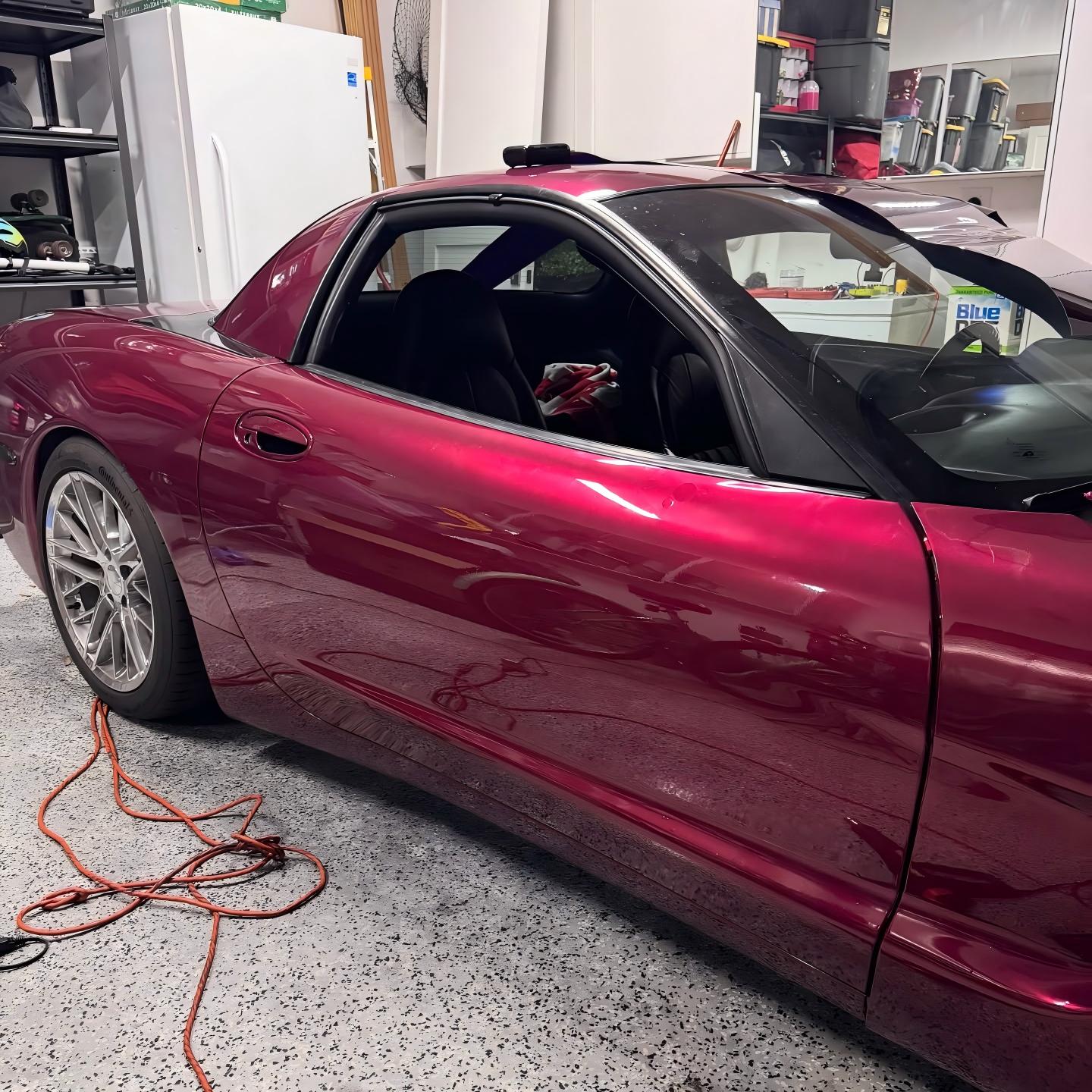 Installing ALUKOCARWRAP gloss metallic car wrap PET on a vehicle wing, demonstrating strong adhesive conformability.