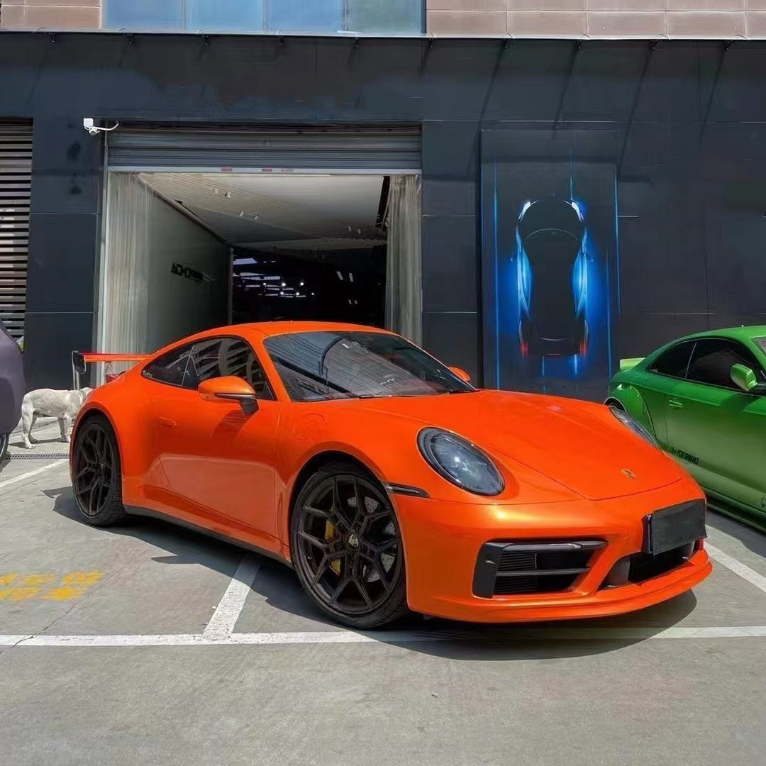 Gloss metallic paint orange car vinyl wrap with PET liner installed on a luxury sports car, showing a mirror-like vibrant finish.