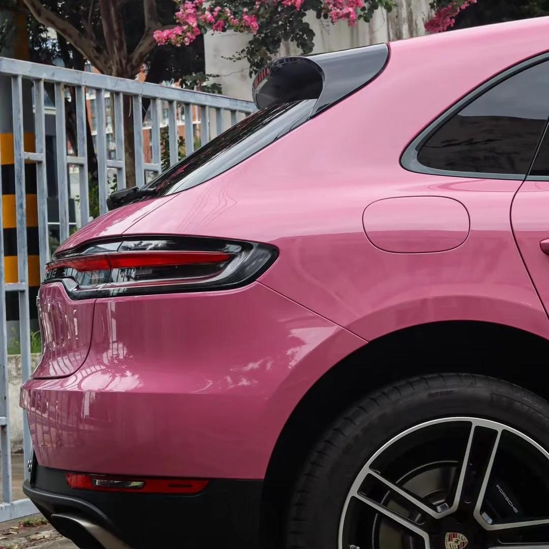 Macro focus of the flexible pink car wrap contouring around a complex rear bumper diffuser, showcase of high thermal stretching agility.