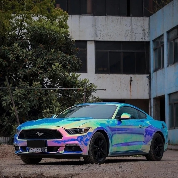 A sports car wrapped in premium rainbow laser blue vinyl showcasing an intense chrome electroplated shifting color effect under daylight.