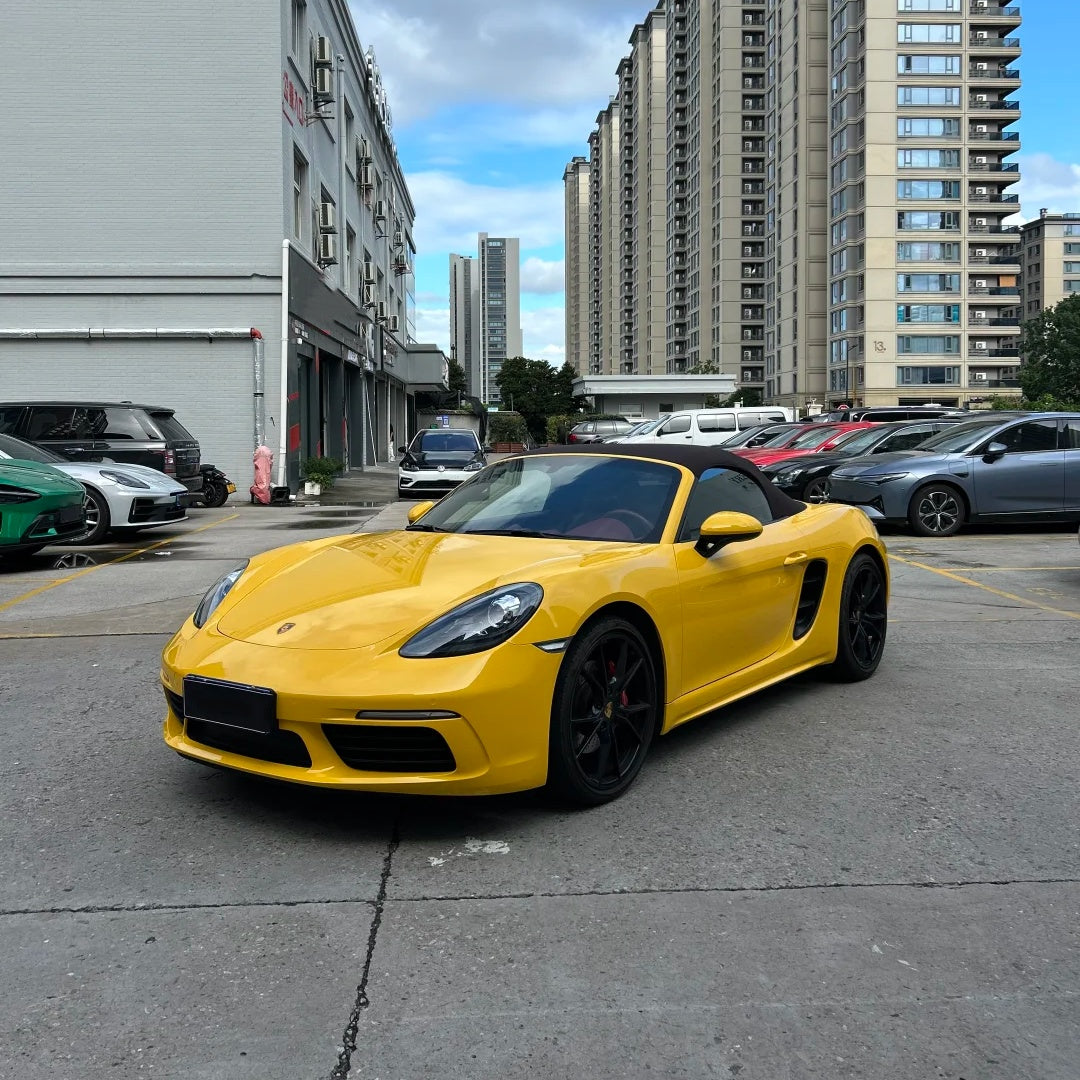 Exotic supercar wrapped in ALUKOCARWRAP TPU sunflower yellow PPF parked outdoors under harsh bright sunlight, showing a hyper-saturated gloss.