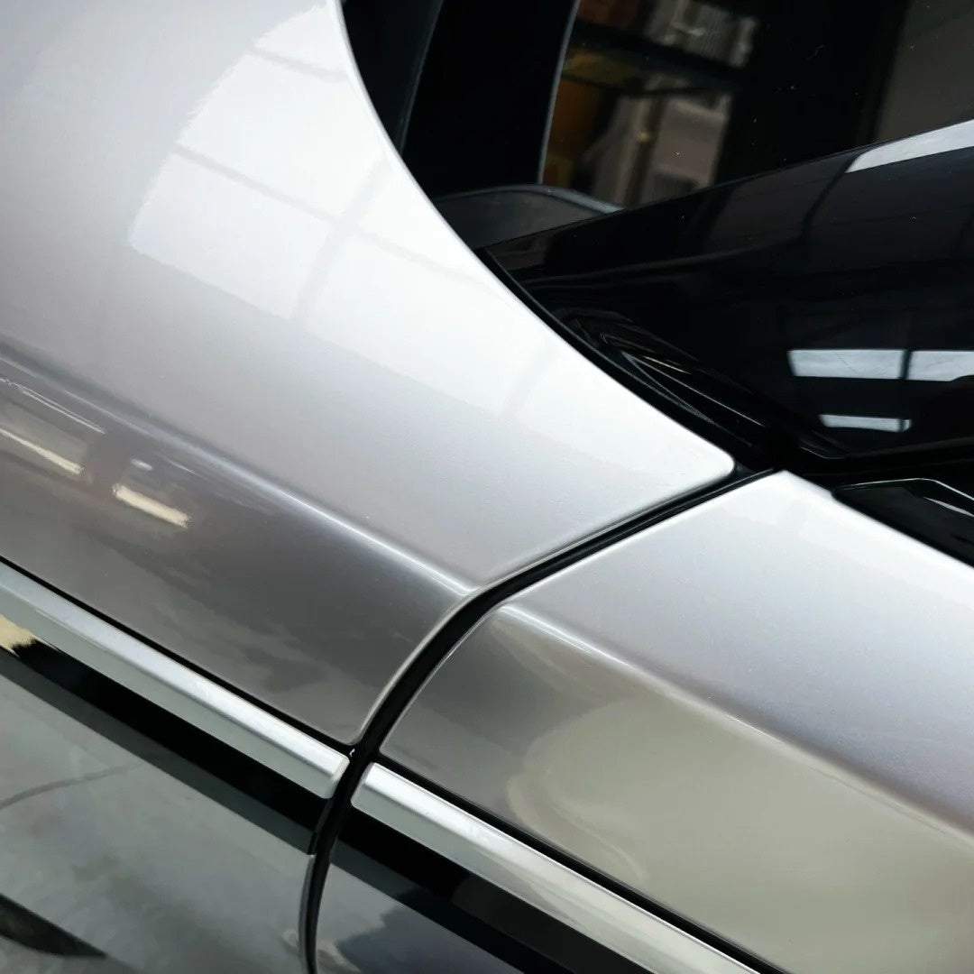 Close-up on dynamic body lines wrapped in premium Gloss Silver Car Wrap with an intense liquid shine.