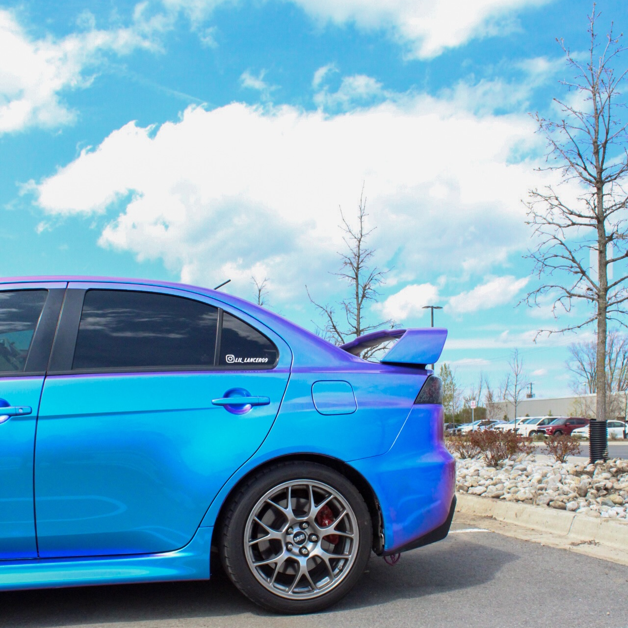 Close-up of gloss purple car wrap shifting to chameleon blue vinyl wrap under bright outdoor sunlight.