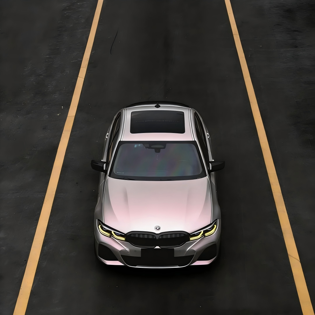 Side panel view of a car wrapped in metallic chameleon vinyl wrap, shifting from metallic silver car wrap to frosted rose quartz tones under natural shadow.
